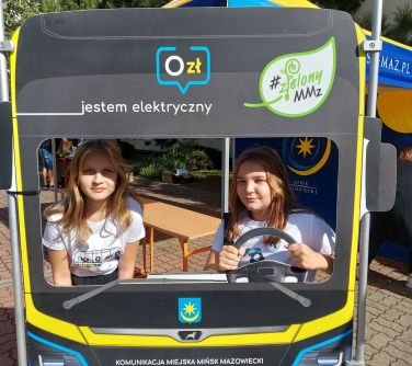 dwie nastolatki pozują do zdjęcią w makiecie przodu autobusu