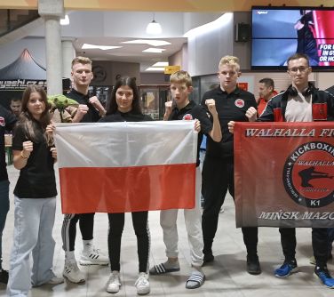 grupa osób pozuje do zdjęcia w srodku nastolatka trzyma w dłoniach flagę Polski oraz nastolatek flagę klubu Walhalla,...