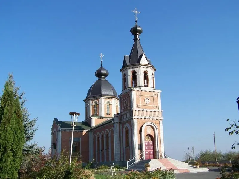 Ceglana cerkiew z dwoma kopułami i wysoką wieżą z dzwonnicą, zwieńczonymi krzyżami.