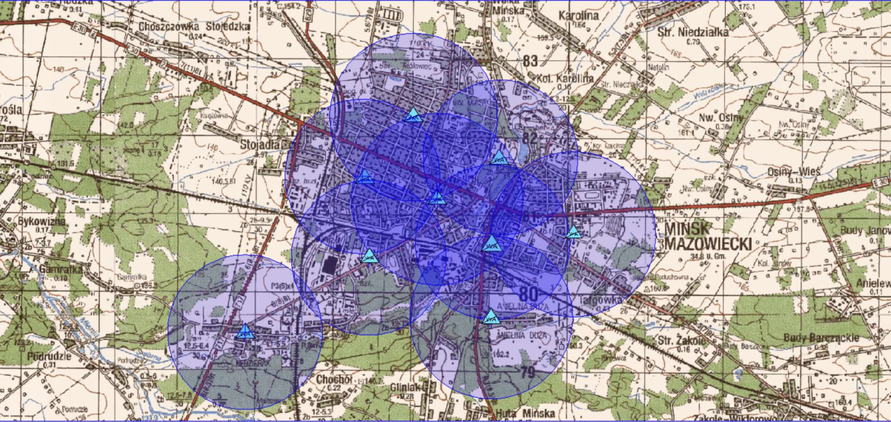 Mapa miasta Mińsk Mazowiecki z zaznaczonymi niebieskimi okręgami i symbolami trójkątów rozmieszczonymi na terenie miasta.