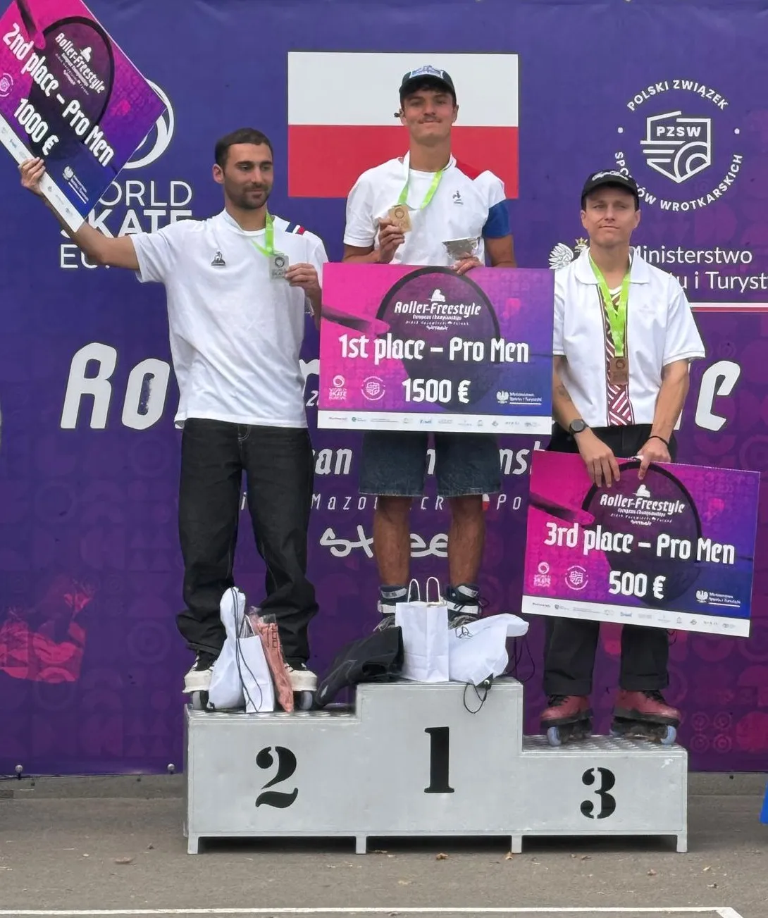 Trzech mężczyzn stoi na podium z nagrodami i medalami po zawodach Roller Freestyle, każdy trzyma tabliczkę z miejscem i kwotą nagrody, w tle flaga Polski i fioletowy baner z logo oraz napisami.