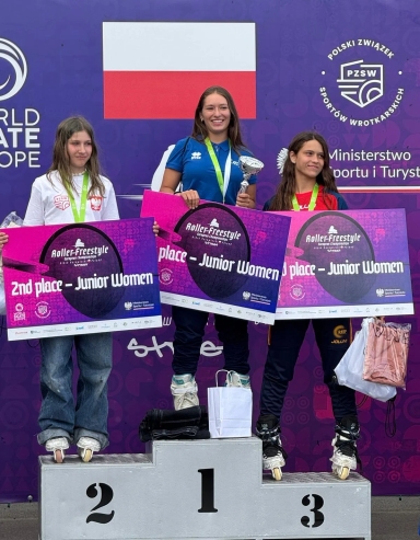 Trzy zawodniczki na podium z medalami i dyplomami za miejsca w konkurencji Junior Women na Roller-Freestyle European Championships przed flagą Polski i banerem PZSW oraz Ministerstwa Sportu i Turystyki.