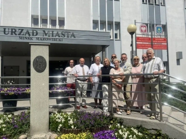 Grupa osób stoi przy barierce przed wejściem do budynku Urzędu Miasta Mińsk Mazowiecki.