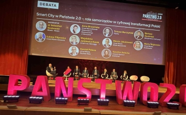 Na scenie siedzi osiem osób uczestniczących w debacie pod dużym ekranem z tytułem i nazwiskami panelistów, a przed sceną stoją duże, czerwone litery układające się w napis „PAŃSTWO 2.0”.