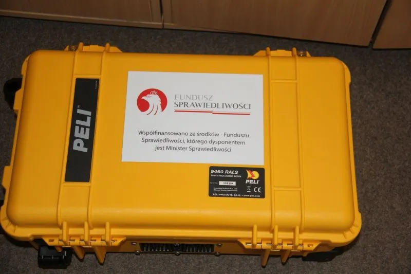 Żółta skrzynka transportowa PELI z naklejką Funduszu Sprawiedliwości i informacją o dofinansowaniu.