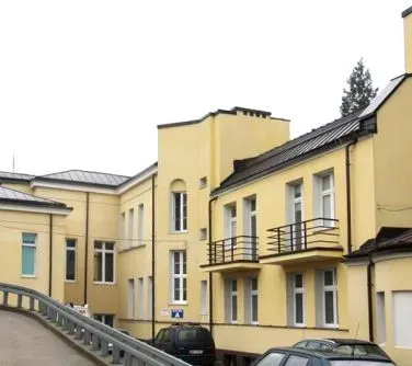 Zabudowania w żółtym kolorze z balkonami i kilkoma zaparkowanymi samochodami.