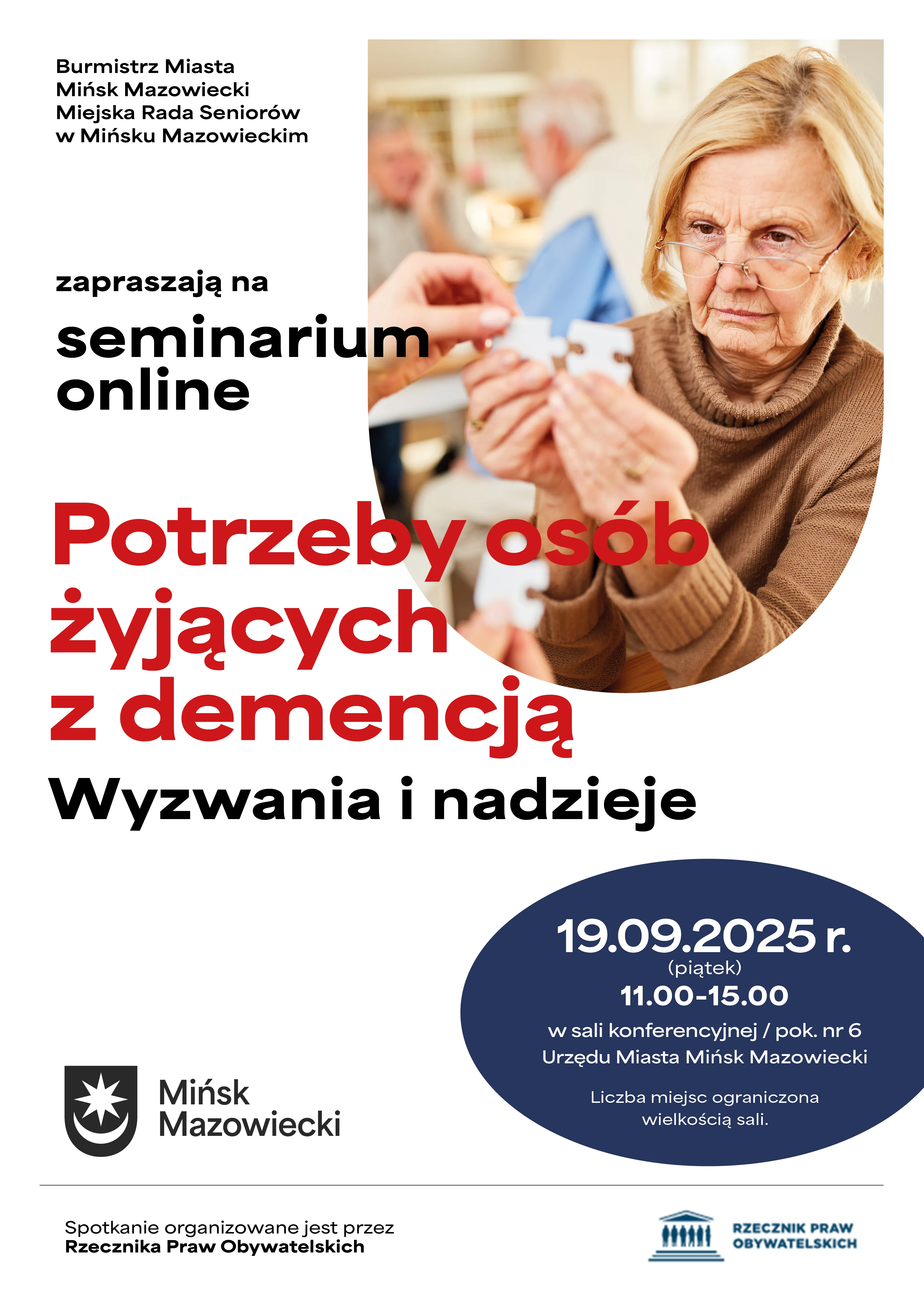 Kliknięcie powiększy obraz. Starsza kobieta z okularami trzyma dwie części puzzli, siedząc przy stole w pomieszczeniu, w tle inni seniorzy.