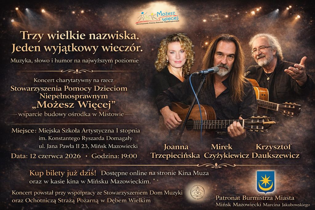 Kliknięcie powiększy obraz. Trzech muzyków stoi na scenie przed ciemnym tłem z ciepłymi punktowymi światłami. Mężczyzna z długimi włosami siedzi na środku, trzyma akustyczną gitarę i śpiewa do mikrofonu. Po lewej stoi kręcona blond kobieta, po prawej starszy mężczyzna w okularach trzyma gitarę. W tle widoczne są dekoracyjne, złote świetlne efekty i kilka logotypów.