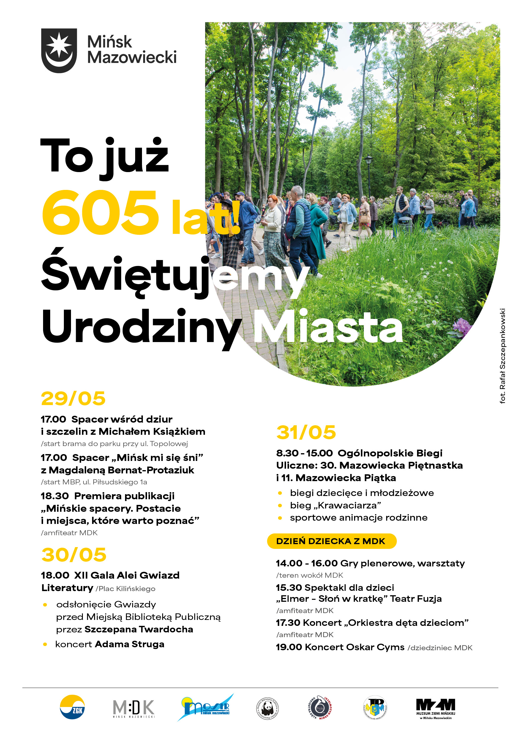 Kliknięcie powiększy obraz. Plakat z białym tłem i dużym okrągłym zdjęciem po prawej stronie. W zdjęciu około dwudziestu osób idzie alejką w zielonym parku w ciągu dnia. Na górze po lewej czarny herb i nazwa miasta. Po lewej i u dołu kolumny czarnych i żółtych nagłówków oraz listy wydarzeń. Trawiaste zarośla i drzewa dominują w prawej części zdjęcia.