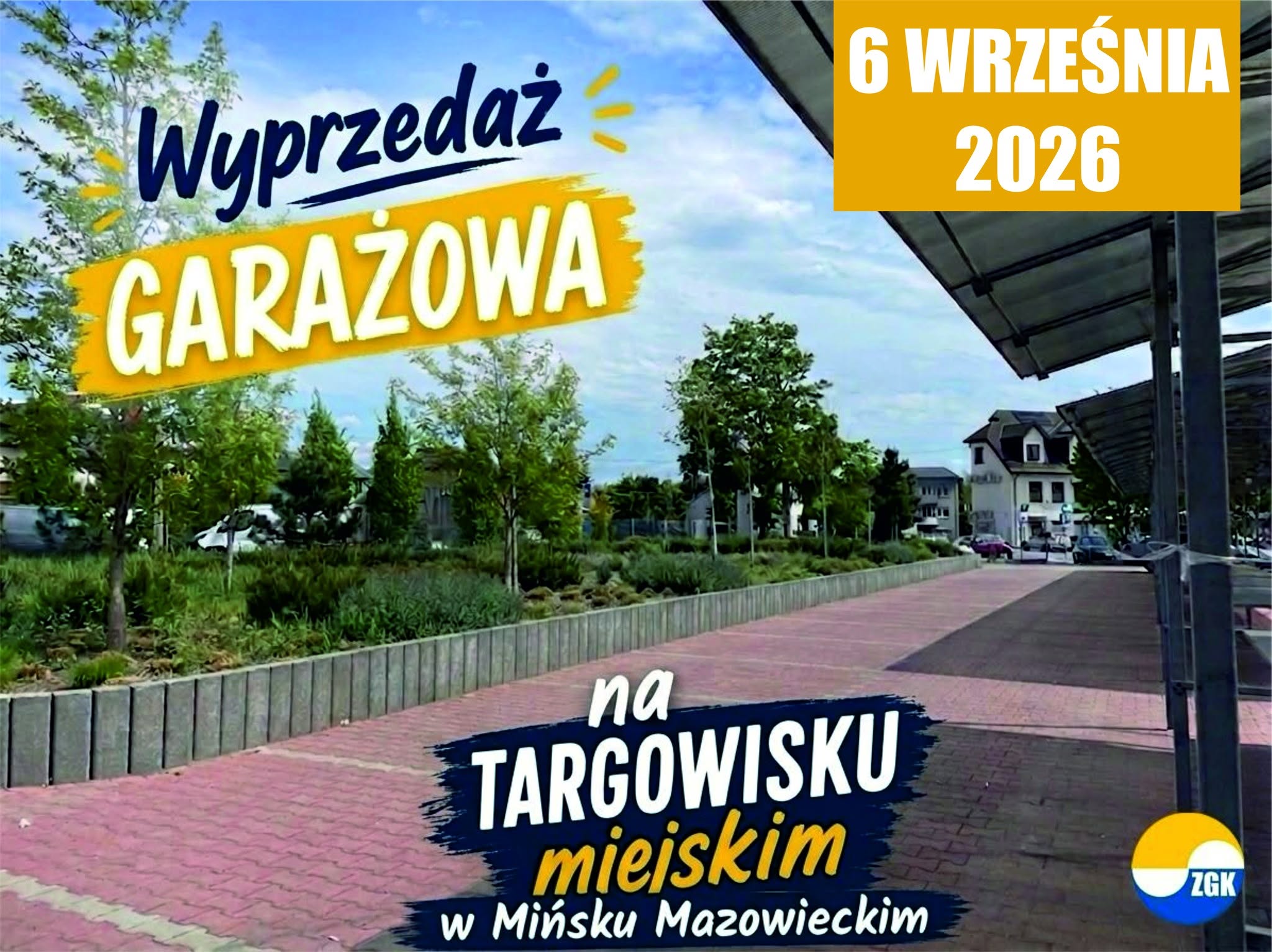 Kliknięcie powiększy obraz. Zewnętrzny plac targowy z brukowanym chodnikiem na pierwszym planie. Po prawej zadaszone stanowiska handlowe na metalowych podporach. Po lewej rząd drzew i pas zieleni z niskimi krzewami. W tle niska zabudowa mieszkalna i częściowo zachmurzone niebo z dużymi kolorowymi banerami.