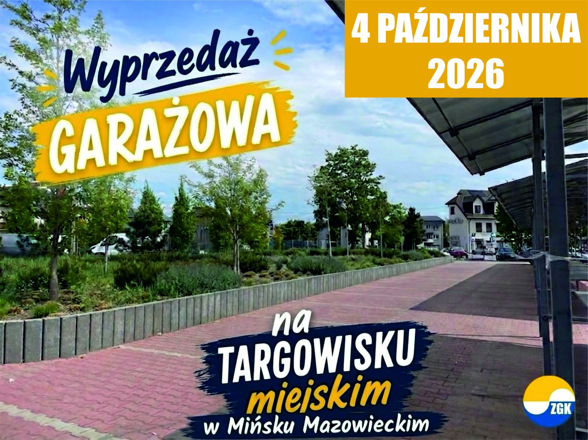 Kliknięcie powiększy obraz. Zewnętrzny deptak z różowymi kostkami brukowymi obok niskiego murku i pasów zieleni z drzewami. Po prawej widać zadaszone miejsca parkingowe i budynki w tle, na niebie jasne chmury, a w górnej części kolorowe banery promocyjne.