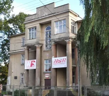 Budynek z dużymi kolumnami i dwoma banerami zawieszonymi na fasadzie.