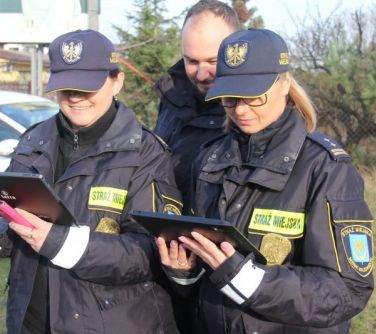 Dwie strażniczki i strażnik miejski patrzą w tablety