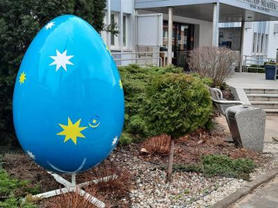 Duże jajo dekoracyjne na metalowym stojaku, koloru niebieskiego w żółte i białe gwiazdki przed urzędem miasta