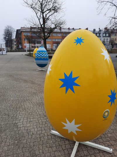 Duże jajo dekoracyjne na metalowym stojaku, koloru żółtego w niebieskie i białe gwiazdki
