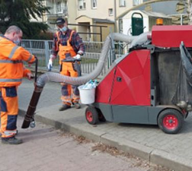 Pracownicy ZGK w pomarańczowych uniformach, sprzatają ulice miasta korzystając z nowej maszyny sprzątającej, zasilanej...