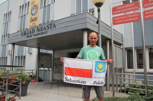 Sebastian Reczek przed Urzędem Miasta z polską flagą