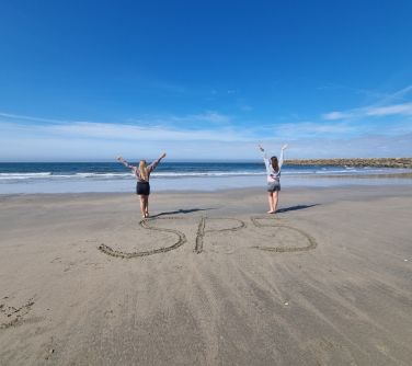 Uczniowie na plaży. Napis na piasku SP 5