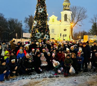 Grupowe zdjęcie uczestników Mikołajek. W tle choinka na Starym Rynku.