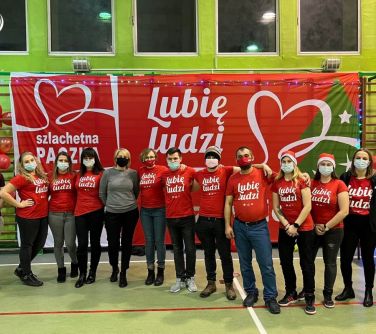 Wolontariusze akcji Świąteczna Paczka razem z Katarzyną Łaziuk w tle napis Lubię ludzi.