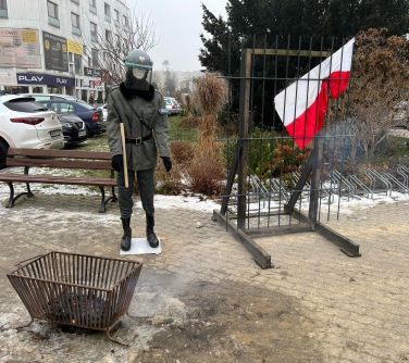 Milicjant - manekin, koksownik i kraty z biało-czewona flagą - symbol tamtych dni.