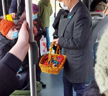 Burmistrz Miasta podczas podróży autobusem rozdaje paniom słodkie upominki z okazji Dnia Kobiet.