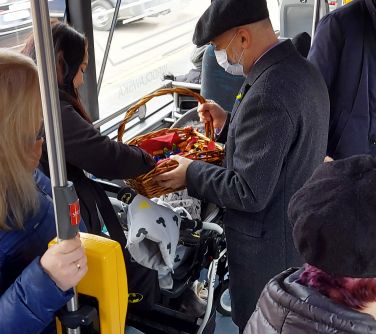 Burmistrz miasta poczas jazdy próbnej autobusem rozdaje paniom słodkie upominki i lusterka z okazji Dnia Kobiet.