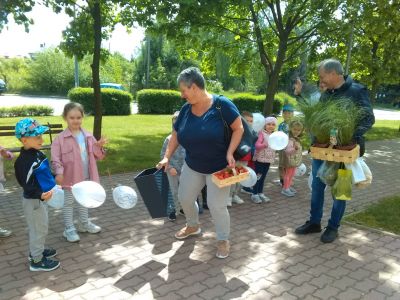 Dwór, słońce. Grupa dzieci i dwoje opiekunów. Trzymają białe balony
