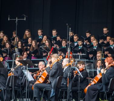 Na pierwszym planie orkiestra symfoniczna, na drugim chór