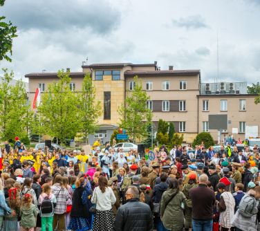 Na dworze, w ciągu dnia. Pochmurnie. Zgromadzona duża grupa osób. W tle budynki