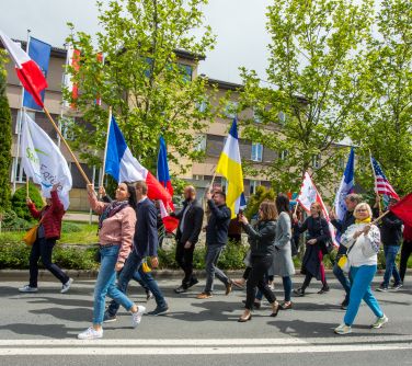 Dzień, słońce. Grupa osób maszezruje ulicą. Machają flagami