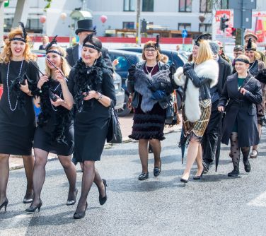 Dzień, słońce. Ulicami maszerują osoby  przebraniach. Kobiety na czarno