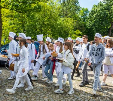 Słoneczny dzień. Alejka idą dzieci w białych przebraniach lekarskich