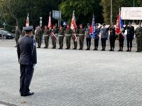 Dowódca w mundurze stoi przed zastępem żołnierzy