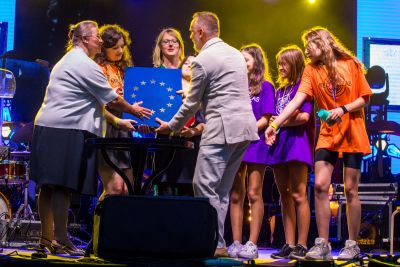 wręczenie nagrody Europejskiej, osoby trzymają niebieskie pudełko z gwiazdkami