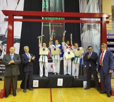 zawodniczki stoją na podium, trzymają w górze statuetki