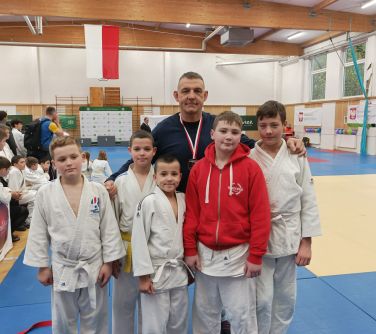 młodzi zawodnicy judo pozują do zdjęcia z mężczyzną