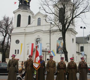 poczet z ułańskim sztandarem, w tle kościół