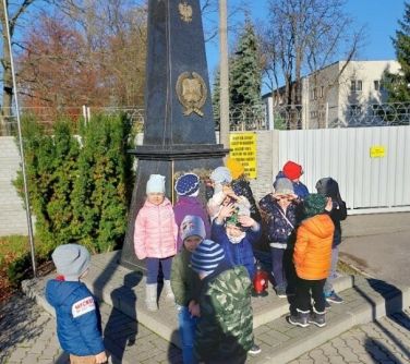 przedszkolaki pozują do zdjęcia przy pomniku Związku Inwalidów Wojennych