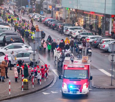 Dzień, zimą. Na ulicy przy rondzie, samochód za nią kareta i dzieci