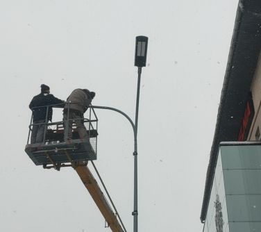 mężczyżni stojący na podnośniku wymieniają oświetlenie