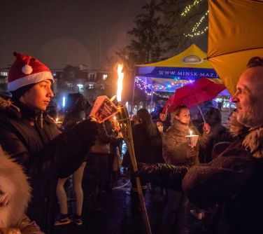 mężczyzna odpala lampion od pochodni p. Burmistrza