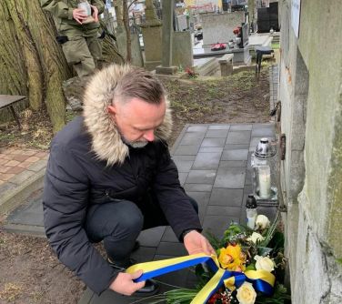 mężczyzna składa bukiet przy grobie