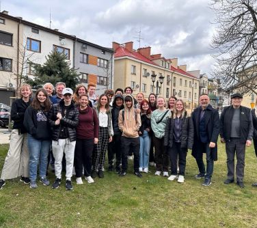 osoby pzują do zdjęcia stojąc na trawie