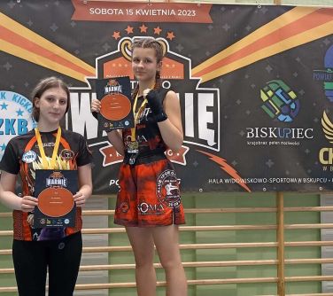 dwie nastolatki pozują na podium, w tle baner