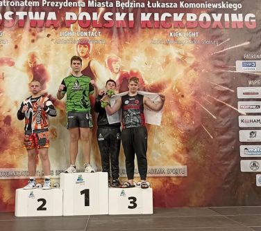 czterech chłopców pozuje na podium w tle baner