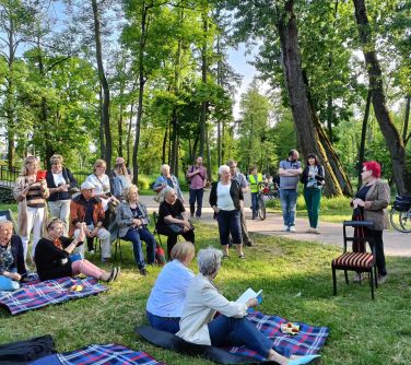 piknik na trawie, osoby siedzą na leżakach, kocach