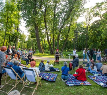 piknik na trawie, osoby siedzą na leżakach, kocach