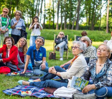 piknik na trawie, osoby siedzą na leżakach, kocach