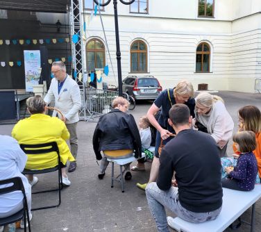 osoby siedzą na koncercie pomięzy nimi kobieta i mężczyzna w koszykach rozdają lizaki i czekoladki